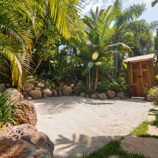 White sand beach with green lush vegetation, palms, tropical boulders and Bali gate