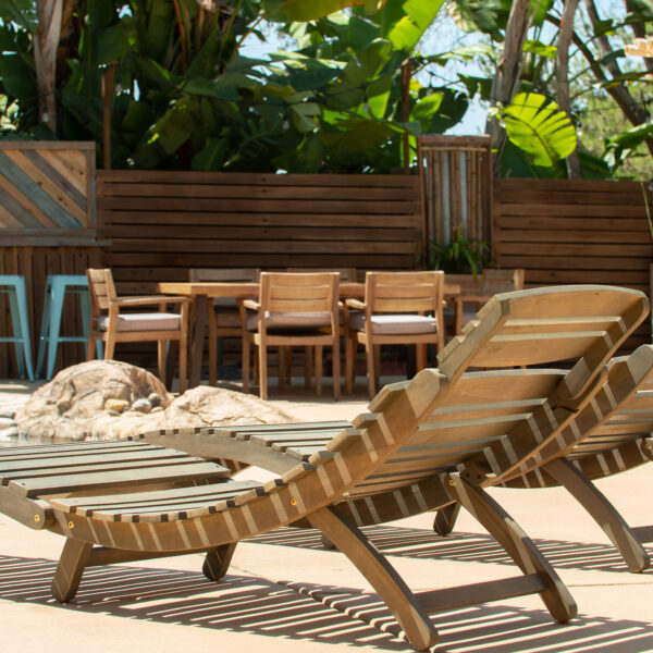 Dual lounge chairs with outdoor seating and decorative wall in background at Tropic Shots production set